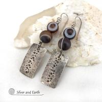 These handcrafted sterling silver earrings feature sterling silver rectangles with a hammered and hand stamped texture accented with natural Botswana agate gemstones. The stones have a smoky brown hue with a natural orbicular "eye" and line pattern. Botswana agate is a unique, banded chalcedony from Southern Africa. Bold and unique, these earrings are one-of-a-kind and will make a striking statement. They'll make a great gift for a natural stone lover. 