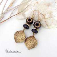 These handcrafted gold brass earrings have a contemporary modern style with an ethnic boho vibe. They feature brass drops with a lightly hammered texture accented with Tibetan eye agate gemstones, black glass and shiny brass beads. Bold and unique, they'll make a striking statement. Handmade in the USA by Silver and Earth Jewelry. 