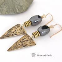 These gold brass triangle earrings have a hand stamped texture and are accented with natural hematite nugget-shaped gemstones on top of a stack of tiny brass beads. They have a modern contemporary and edgy style that makes a bold statement.