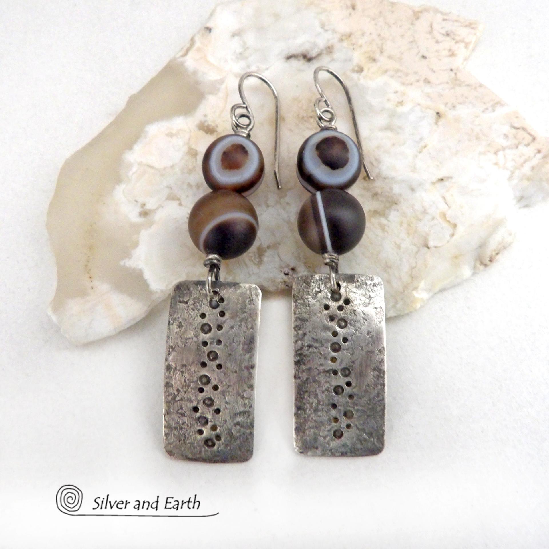 These handcrafted sterling silver earrings feature sterling silver rectangles with a hammered and hand stamped texture accented with natural Botswana agate gemstones. The stones have a smoky brown hue with a natural orbicular "eye" and line pattern. Botswana agate is a unique, banded chalcedony from Southern Africa. Bold and unique, these earrings are one-of-a-kind and will make a striking statement. Handmade in the USA by Silver and Earth Jewelry. 
