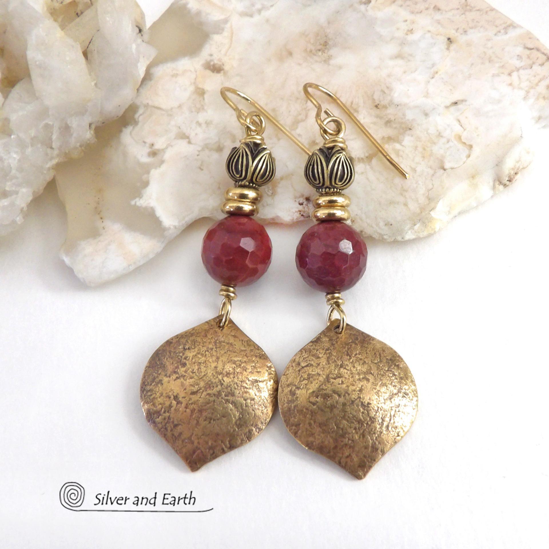 These handcrafted gold brass earrings have a hammered raw silk texture and are accented with micro-faceted burgundy mookaite gemstones, tiny brass beads and tulip flower-shaped beads. Mookaite is a unique, colorful type of jasper that is found at the Mooka Creek in Western Australia. It's known for distinct colors of burgundy, yellows, pinks, and purples. These earrings have a modern elegant chic style that coordinates beautifully with all wardrobe types. Handmade in the USA by Silver and Earth Jewelry. 