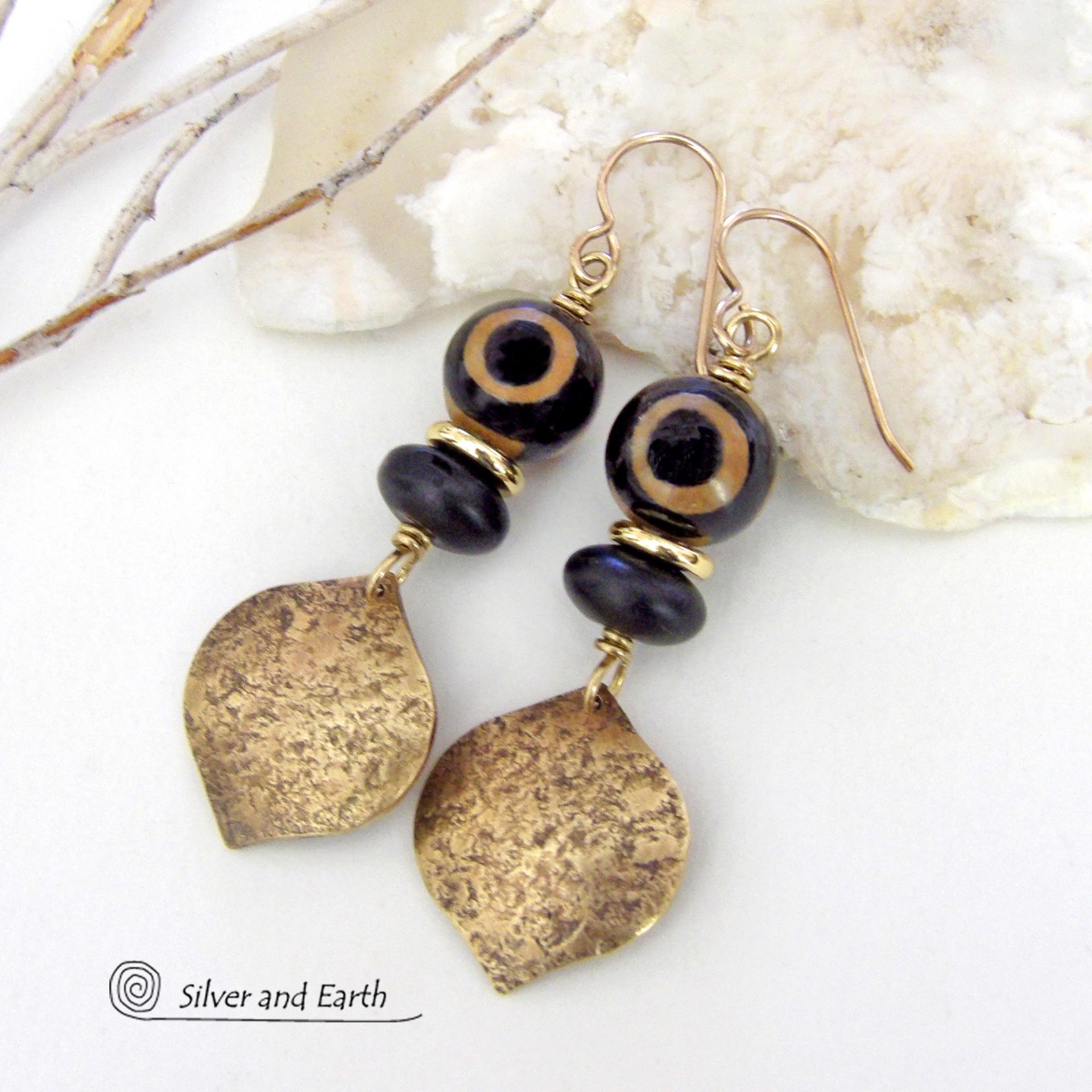 These handcrafted gold brass earrings have a contemporary modern style with an ethnic boho vibe. They feature brass drops with a lightly hammered texture accented with Tibetan eye agate gemstones, black glass and shiny brass beads. Bold and unique, they'll make a striking statement. Handmade in the USA by Silver and Earth Jewelry. 