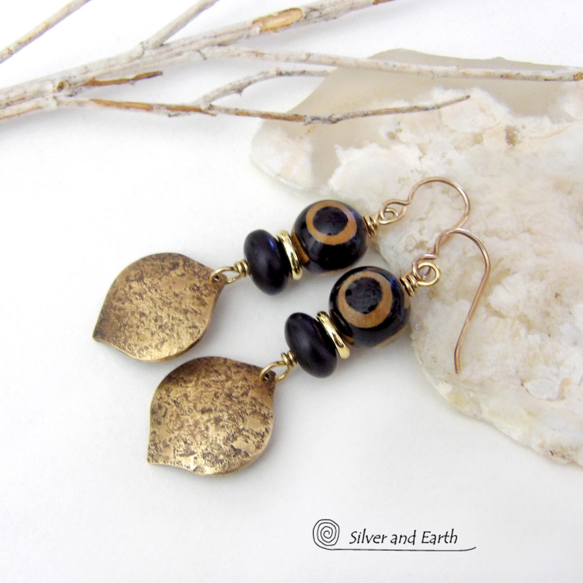 These handcrafted gold brass earrings have a contemporary modern style with an ethnic boho vibe. They feature brass drops with a lightly hammered texture accented with Tibetan eye agate gemstones, black glass and shiny brass beads. Bold and unique, they'll make a striking statement. Handmade in the USA by Silver and Earth Jewelry. 