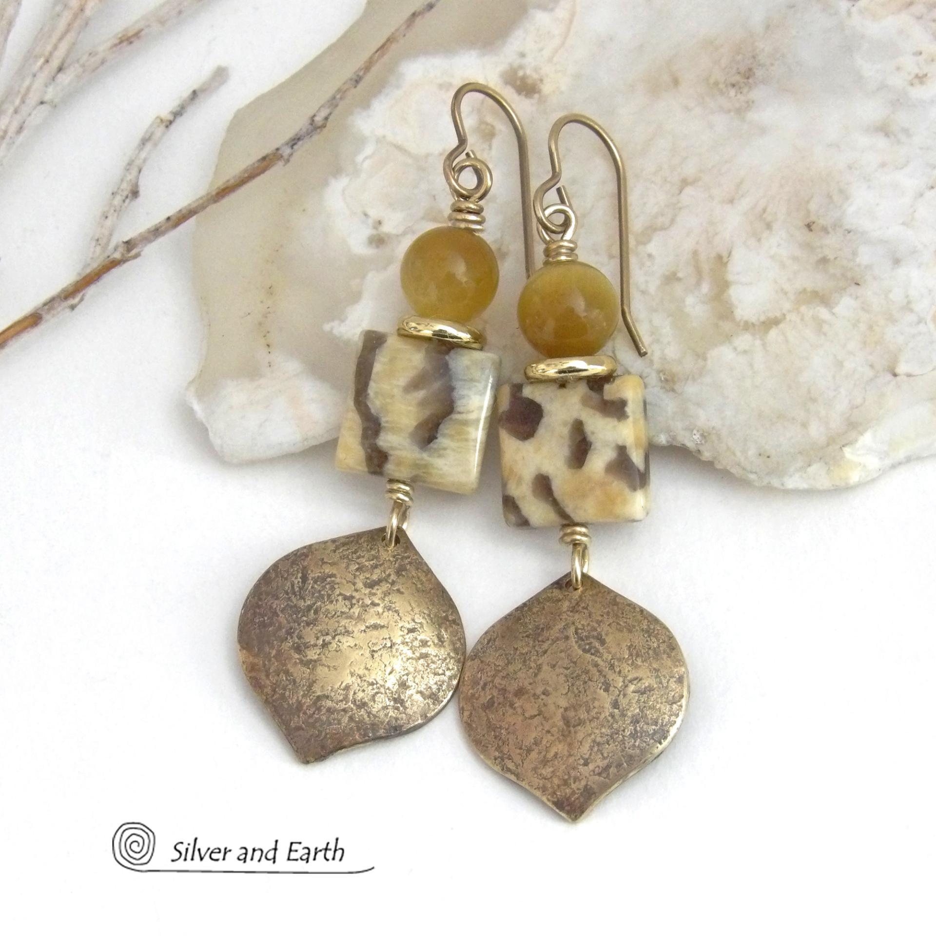 These handcrafted earrings feature shiny gold brass dangles with a hammered raw silk texture accented with graphic feldspar and golden tiger's eye gemstones and shiny brass beads. Graphic feldspar is a type of moonstone that has smoky quartz inclusions which creates unique natural patterns. They have an elegant, modern chic style that looks great dressed up or down. Handmade in the USA by Silver and Earth Jewelry. Total length of approx. 2-3/8" from top of brass ear wires and 3/4" at widest point.