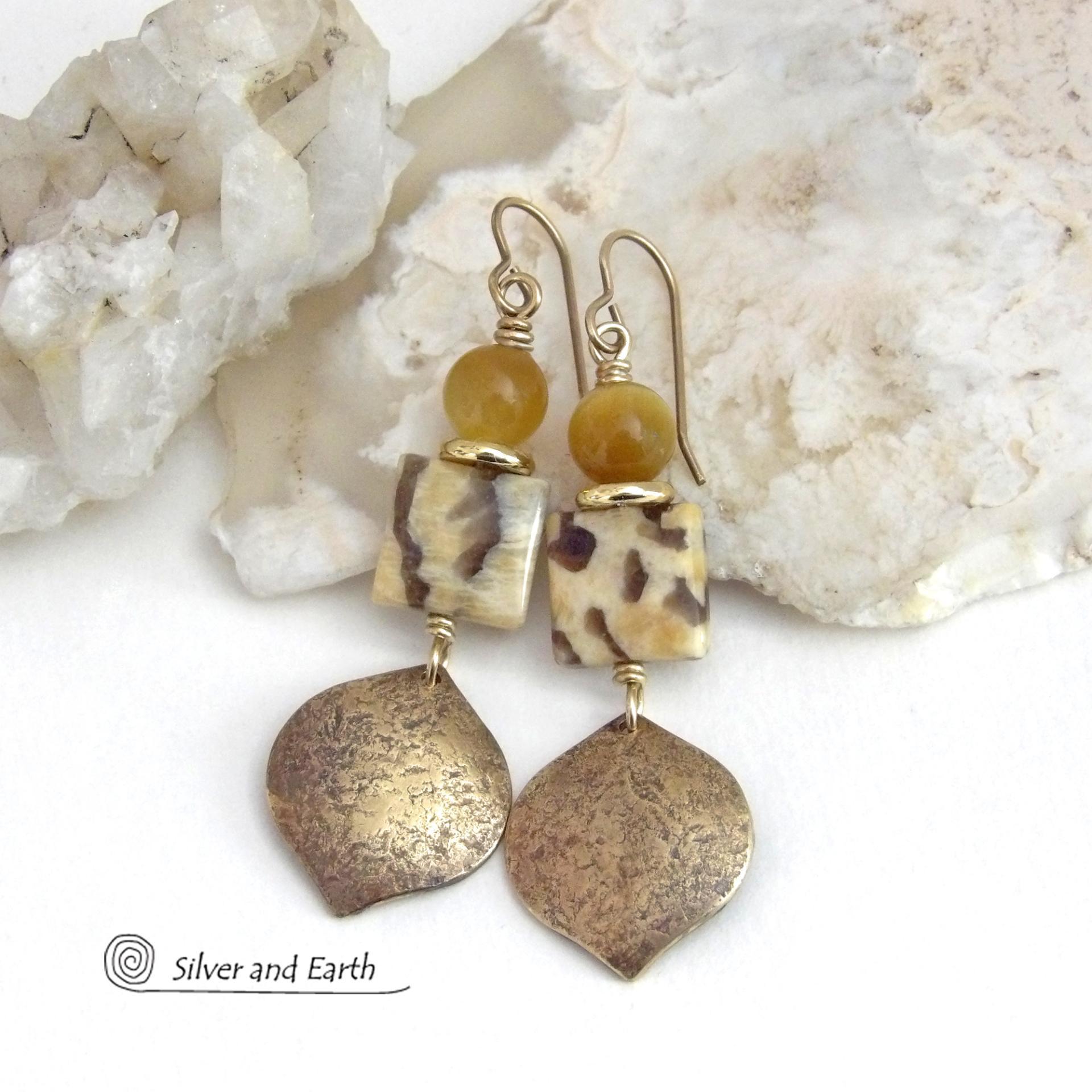 These handcrafted earrings feature shiny gold brass dangles with a hammered raw silk texture accented with graphic feldspar and golden tiger's eye gemstones and shiny brass beads. Graphic feldspar is a type of moonstone that has smoky quartz inclusions which creates unique natural patterns. They have an elegant, modern chic style that looks great dressed up or down. Handmade in the USA by Silver and Earth Jewelry. Total length of approx. 2-3/8" from top of brass ear wires and 3/4" at widest point.