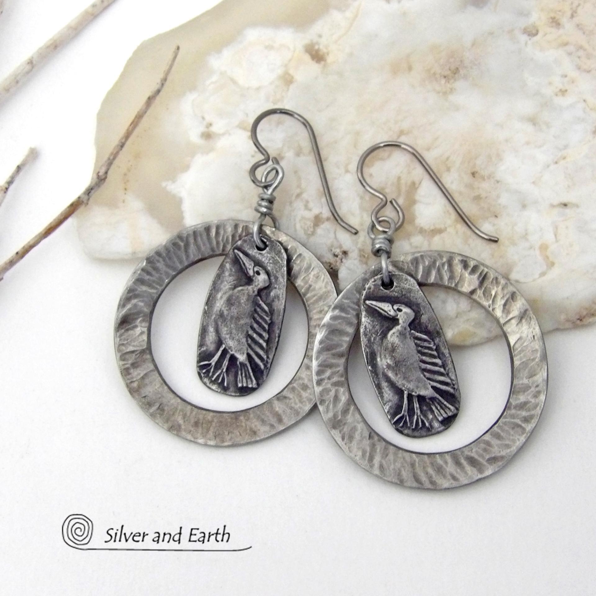These handcrafted earrings feature silver pewter circle hoops with a hammered texture accented with silver pewter bird charms dangling in front. Lightweight and comfortable to wear, they have a casual earthy style with rustic flair that coordinates with all wardrobe types. They'll make a great gift for a nature / bird lover - or a unique addition to your own jewelry wardrobe. Handmade in the USA by Silver and Earth Jewelry.