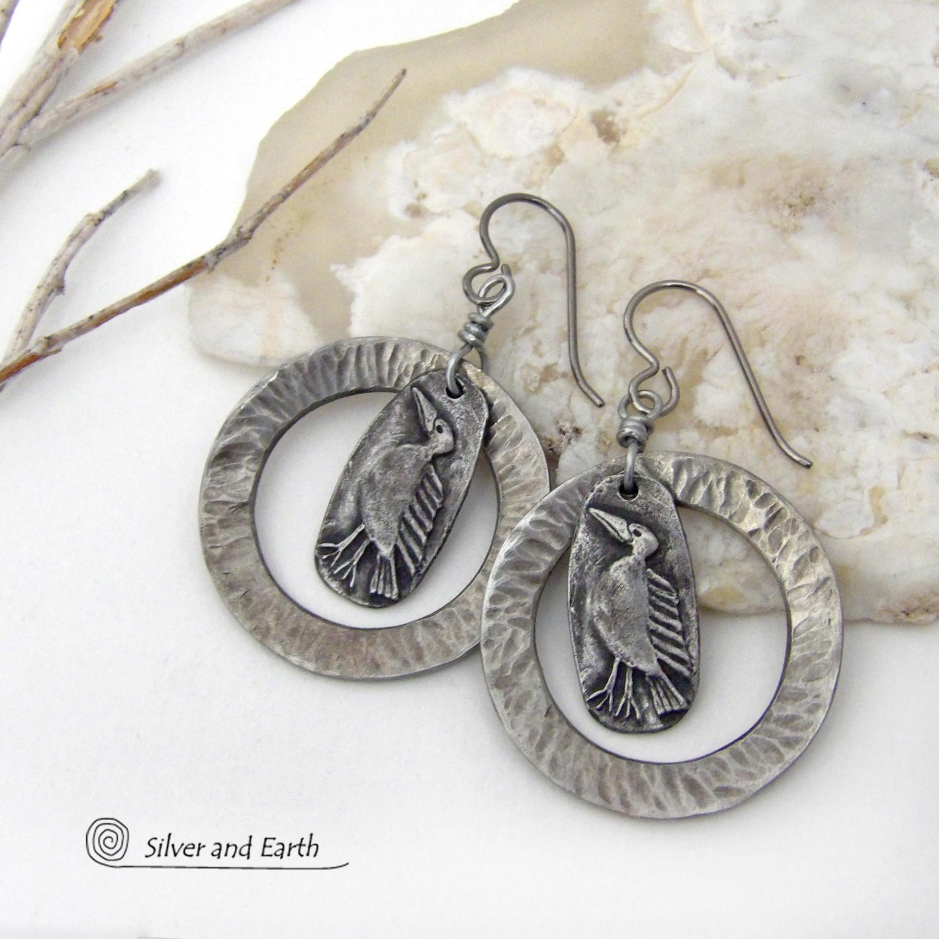 These handcrafted earrings feature silver pewter circle hoops with a hammered texture accented with silver pewter bird charms dangling in front. Lightweight and comfortable to wear, they have a casual earthy style with rustic flair that coordinates with all wardrobe types. They'll make a great gift for a nature / bird lover - or a unique addition to your own jewelry wardrobe. Handmade in the USA by Silver and Earth Jewelry.