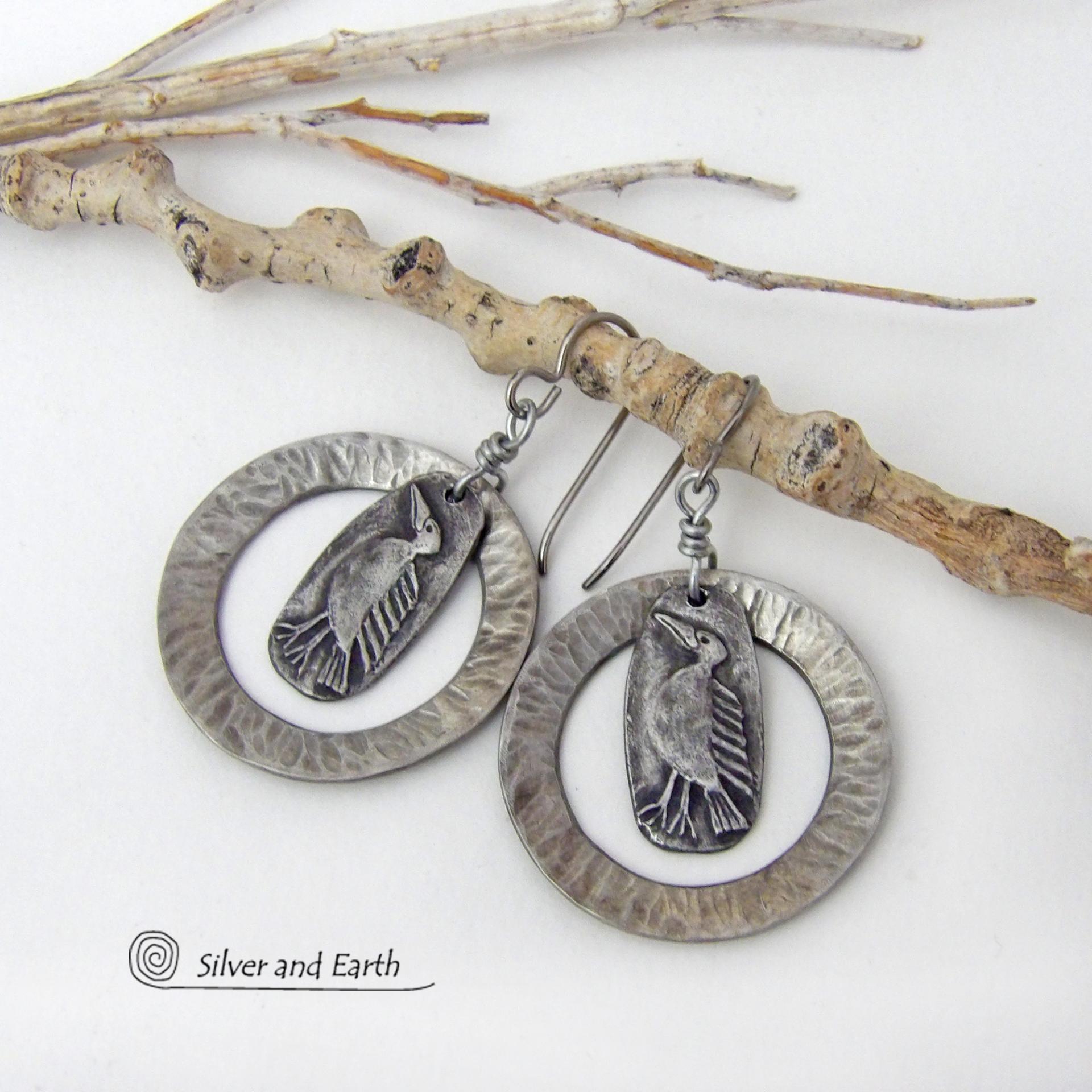 These handcrafted earrings feature silver pewter circle hoops with a hammered texture accented with silver pewter bird charms dangling in front. Lightweight and comfortable to wear, they have a casual earthy style with rustic flair that coordinates with all wardrobe types. They'll make a great gift for a nature / bird lover - or a unique addition to your own jewelry wardrobe. Handmade in the USA by Silver and Earth Jewelry.