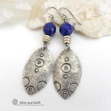 These handcrafted sterling silver earrings have an exotic, Egyptian inspired vibe. The design consists of sterling dangles with a hand stamped texture accented with faceted lapis lazuli gemstones and small pewter beads. Bold and unique - they'll make a striking statement and will add a touch of cultural exotic charm to any outfit.