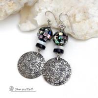 These handcrafted sterling silver earrings feature an abstract hand stamped texture and are accented with inlaid abalone shell mosaic, black onyx and mother-of-pearl beads. The abalone beads resemble disco balls and have a beautiful rainbow iridescence of various colors. Bold and unique, they have a modern contemporary style and will make a striking statement. Handmade in the USA by Silver and Earth Jewelry. Length: approx. 2-1/8” from top of sterling silver ear wires and 7/8". 