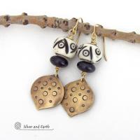 These handcrafted gold brass earrings have an ethnic, boho tribal vibe that makes a unique bold statement. They feature brass drops with a hand stamped texture accented with African carved bone beads with a bold pattern of dots and lines and matte black glass beads. Perfect for women that love unique handmade jewelry. Handmade in the USA by Silver and Earth Jewelry.