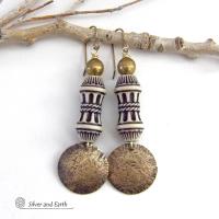 Bold and unique, these handcrafted earrings have an ethnic African tribal vibe. They feature gold brass dangles with a hammered rustic texture accented with exotic African beads with an intricate brown and white carved pattern topped off with gold brass beads. Unique and fun to wear - they'll make a bold, striking statement. Perfect for women that love to wear one-of-a-kind artisan handcrafted jewelry. Handmade in the USA by Silver and Earth Jewelry. 