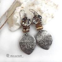 These handcrafted sterling silver earrings have a funky edgy vibe with ethnic tribal flair. They feature rustic hammered sterling silver dangles accented with African batik, bone and brown coconut shell beads. Bold and exotic, they'll add a touch a bohemian tribal style to your wardrobe that is sure to make a statement.