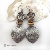 Unique and one of a kind, these handcrafted sterling silver earrings have a funky edgy vibe with ethnic tribal flair. They feature rustic hammered sterling silver dangles accented with African batik, bone and brown coconut shell beads. Bold and exotic, they'll add a touch a bohemian tribal style to your wardrobe that is sure to make a statement.