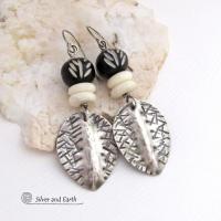 Handcrafted sterling silver earrings with a bold, ethnic tribal flair featuring hand textured sterling dangles accented with African black bone beads with a carved white pattern and white bone beads.