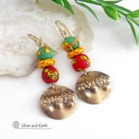 Bold and unique - these gold brass dangle earrings will surely brighten your day! They feature bright and colorful African glass beads with beautiful hues of green, red and yellow. They are accented with handcrafted gold brass dangles with a hammered organic texture. The African beads are handcrafted by artisans in Ghana from recycled glass by a traditional process passed down thru many generations. These earrings have a bohemian Afrocentric style with lots of fashionable flair! 