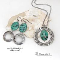 This handcrafted pendant necklace features a natural African turquoise gemstone dangling in front of a silver tone pewter circle with a hand stamped texture and oxidized finish. Unique and one of a kind, it has an earthy organic style with southwestern flair. Coordinating earrings sold separately.