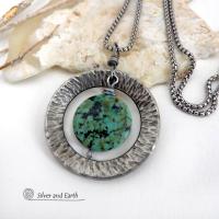 This handcrafted pendant necklace features a natural coin-shaped African turquoise gemstone framed against a hammered and oxidized silver tone pewter circle. It has a modern earthy organic style that coordinates well with all wardrobe types. The design is versatile and can be worn by either a man or woman. It will make a great gift for anyone that loves natural stone jewelry. Handmade in the USA by Silver and Earth Jewelry. 
