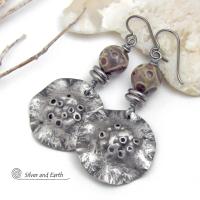 These handcrafted earrings have a bold edgy vibe. They feature rustic hammered silver tone pewter dangles accented with natural asteroid jasper stones and stainless steel beads. This type of stone is known for its unique dotted matrix in earth-tone hues of brown, gray and tan. Bold and striking - they're sure to make a statement. Perfect for women that love unique natural stones and artisan handmade jewelry. Handmade in the USA by Silver and Earth Jewelry. 