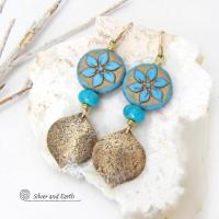 These handcrafted earrings feature gold brass dangles with a lightly hammered raw silk texture accented with glass flower beads and turquoise stone beads. The flower beads are a pretty shade of blue with golden highlights. They have an intricate carved and raised pattern on both sides of the beads. These earrings have a modern elegant, earthy chic style and will make a great gift for anyone that loves flowers and nature. They'll make a great addition to your spring / summer wardrobe - or any time of year.
