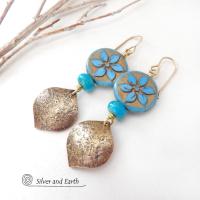 These handcrafted earrings feature gold brass dangles with a lightly hammered raw silk texture accented with glass flower beads and turquoise stone beads. The flower beads are a pretty shade of blue with golden highlights. These earrings have a modern elegant, earthy chic style and will make a great gift for anyone that loves flowers and nature.  The earrings are a beautiful and stylish way to add a touch of elegance to any outfit.