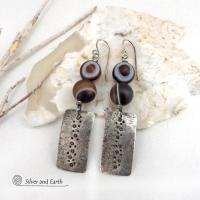 These handcrafted sterling silver earrings feature sterling silver rectangles with a hammered and hand stamped texture accented with natural Botswana agate gemstones. The stones have a smoky brown hue with a natural orbicular "eye" and line pattern. Botswana agate is a unique, banded chalcedony from Southern Africa. Bold and unique, these earrings are one-of-a-kind and will make a striking statement.