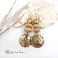 Creamy beige agate stones are accented with textured gold brass dangles and brass beads in these handcrafted earrings. The stones have a creamy beige and tan hue with a natural light brown speckled matrix. They have an earthy, modern style that coordinates beautifully with all wardrobe types.These handcrafted earrings showcase a unique blend of textures and patterns, perfect for adding a touch of bohemian style to any outfit. 