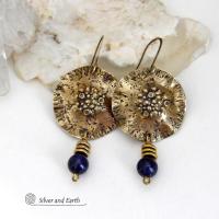 These handcrafted gold brass earrings have a rustic, hammered texture and are accented with dangling blue goldstones and small brass beads. They have a modern chic style with an earthy, organic vibe. Goldstone is a man-made stone of quartz sand glass infused with copper particles which creates the subtle sparkle effects. It was invented in Venice, Italy in the seventeenth century. Handmade in the USA by Silver and Earth Jewelry. 
