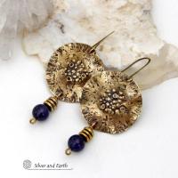 These handcrafted gold brass earrings have a rustic, hammered texture and are accented with dangling blue goldstones and small brass beads. They have a modern chic style with an earthy, organic vibe. Goldstone is a man-made stone of quartz sand glass infused with copper particles which creates the subtle sparkle effects. It was invented in Venice, Italy in the seventeenth century. Handmade in the USA by Silver and Earth Jewelry. 