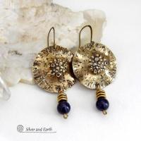 These handcrafted gold brass earrings have a rustic, hammered texture and are accented with dangling blue goldstones and small brass beads. They have a modern chic style with an earthy, organic vibe. Goldstone is a man-made stone of quartz sand glass infused with copper particles which creates the subtle sparkle effects. It was invented in Venice, Italy in the seventeenth century. Handmade in the USA by Silver and Earth Jewelry. 