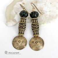 Bold and unique, these handcrafted earrings have an ethnic African tribal vibe. They feature gold brass dangles with a hand stamped and lightly hammered background texture accented with African beads with an intricately carved brownish-black and tan pattern topped off with black African carved bone beads. Unique and fun to wear - they'll make a bold, striking statement. Perfect for women that love to wear one-of-a-kind artisan handcrafted jewelry. Handmade in the USA by Silver and Earth Jewelry.