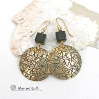 Artisan handcrafted round gold brass earrings with a hand-stamped abstract texture accented with cube-shaped matte black jasper stones on top. They have a modern contemporary vibe that coordinates beautifully with all wardrobe styles.