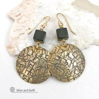 Artisan handcrafted round gold brass earrings with a hand-stamped abstract texture accented with cube-shaped matte black jasper stones on top. They have a modern contemporary vibe that coordinates beautifully with all wardrobe styles.