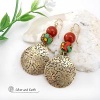 These handcrafted earrings feature gold brass dangles with a hand textured design accented with red jasper gemstones and colorful African glass beads with multi-colored hues of green, red, yellow and black. They have a bold exotic, tribal vibe with a vibrant pop of color that makes a unique statement.