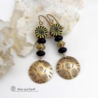 These handcrafted earrings have an ethnic boho tribal vibe. They feature gold brass dangles with a hand stamped spiral and line texture accented with black and light yellow Fimo clay beads with a spiral design, black glass and brass beads. Unique and fun to wear - they have a funky bohemian vibe that makes a bold, striking statement. Perfect for women that love to wear one-of-a-kind artisan handcrafted jewelry. Handmade in the USA by Silver and Earth Jewelry. 