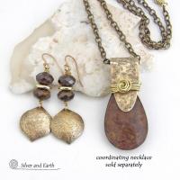 These handcrafted earrings feature gold brass dangles with a hammered organic texture accented with natural bronzite gemstones and shiny gold brass beads. The stones have a beautiful brown hue with a faceted finish which casts off a natural sparkle and shine. They have a modern chic style that coordinates beautifully with all wardrobe types - dressed up or down. A coordinating necklace is available that is sold separately.  Handmade in the USA by Silver and Earth Jewelry.