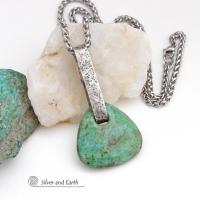 This one-of-a-kind pendant necklace features a beautiful chunky natural chrysocolla gemstone with a faceted finish. The stone is a beautiful shade of bluish-green which resembles turquoise. It hangs from a hand forged solid sterling silver bail with a lightly hammered organic texture. It's reversible. Unique and one-of-a-kind, it's sure to make a statement. Handmade in the USA by Silver and Earth Jewelry.