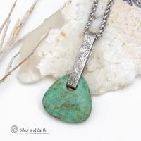 This one-of-a-kind pendant necklace features a beautiful chunky natural chrysocolla gemstone with a faceted finish. The stone is a beautiful shade of bluish-green which resembles turquoise. It hangs from a hand forged solid sterling silver bail with a lightly hammered organic texture. It's reversible. Unique and one-of-a-kind, it's sure to make a statement. Handmade in the USA by Silver and Earth Jewelry.
