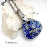 This one-of-a-kind necklace features a gorgeous, chunky and thick natural lapis lazuli gemstone accented with a handcrafted sterling silver bail with a lightly hammered organic texture. The stone is a beautiful shade of blue with white inclusions and a sprinkling of natural sparkly pyrite inclusions and a faceted finish. The stone is equally gorgeous on both sides, so I designed it to be reversible. (See all photos for alternate sides). Pendant comes on a 20" stainless steel chain necklace. 
