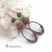 These handmade earrings feature wire wrapped copper oval hoops accented with copper filigree beads, green serpentine gemstones and hand painted wood beads. They have a bold exotic vibe with an ethnic tribal flair and are sure to make a unique statement.