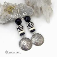 These earrings have a modern style with an ethnic tribal vibe. They feature handcrafted sterling silver circle dangles with a hammered texture accented with black and white Tibetan eye agate gemstones, onyx and bone beads, topped off with round black onyx gemstones with a faceted finish. Unique and striking, they'll make a bold statement. 
