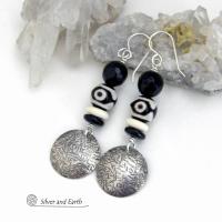These earrings have a modern style with an ethnic tribal vibe. They feature handcrafted sterling silver circle dangles with a hammered texture accented with black and white Tibetan eye agate gemstones, onyx and bone beads, topped off with round black onyx gemstones with a faceted finish. Unique and striking, they'll make a bold statement. 