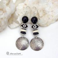 These earrings have a modern style with an ethnic tribal vibe. They feature handcrafted sterling silver circle dangles with a hammered texture accented with black and white Tibetan eye agate gemstones, onyx and bone beads, topped off with round black onyx gemstones with a faceted finish. Unique and striking, they'll make a bold statement. 