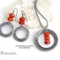 These handcrafted earrings feature silver tone pewter hoops with a hand stamped texture accented with a stack of orange fire agate gemstones. Matching necklace sold separately. 