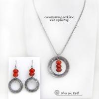 These handcrafted earrings feature silver tone pewter hoops with a hand stamped texture accented with a stack of orange fire agate gemstones. Matching necklace sold separately. 