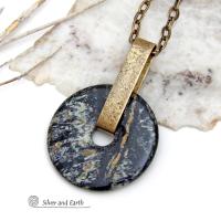 This one-of-a-kind pendant necklace has a large stunning fireworks jasper stone accented with a hand forged gold brass bail. The stone has a natural bold dramatic pattern in hues of black, gold, mint green and cream. The design is modern and bold - yet classic and always in fashion. It can be worn by either a man or women. It's reversible and can be worn on either side. Makes a great gift for a natural stone lover. It comes on a 18" antiqued gold brass chain necklace with lobster claw closure. 