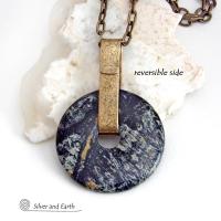 This one-of-a-kind pendant necklace has a large stunning fireworks jasper stone accented with a hand forged gold brass bail. The stone has a natural bold dramatic pattern in hues of black, gold, mint green and cream. The design is modern and bold - yet classic and always in fashion. It can be worn by either a man or women. It's reversible and can be worn on either side. Makes a great gift for a natural stone lover. It comes on a 18" antiqued gold brass chain necklace with lobster claw closure.