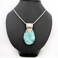 A stunning, natural green moonstone is accented with a handcrafted sterling silver bail in this one-of-a-kind pendant necklace. The stone has a beautiful mint green hue with a creamy white matrix. The bail is accented with twists of oxidized sterling silver wire. Bold and unique, it's sure to make a striking statement. 
