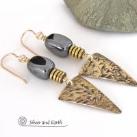 These gold brass triangle earrings have a hand stamped texture and are accented with natural hematite nugget-shaped gemstones on top of a stack of tiny brass beads. They have a modern contemporary and edgy style that makes a bold statement.
