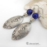  These artisan handcrafted steling silver dangle earrings have a distinct  "Egyptian inspired vibe," evoking the mystique and power of that ancient civilization. The unique design consists of sterling dangles with a hand stamped texture accented with faceted lapis lazuli gemstones. Bold and unique - they'll make a striking statement and will add a touch of cultural exotic charm to any outfit.